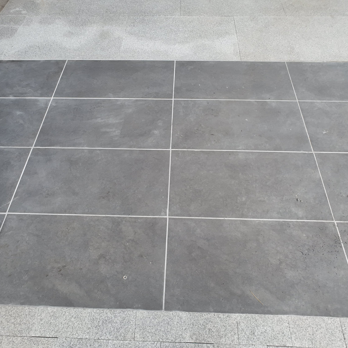 Gray tiled floor with a corner showing a step and wall.