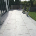 Paved patio area with potted plants in a garden setting